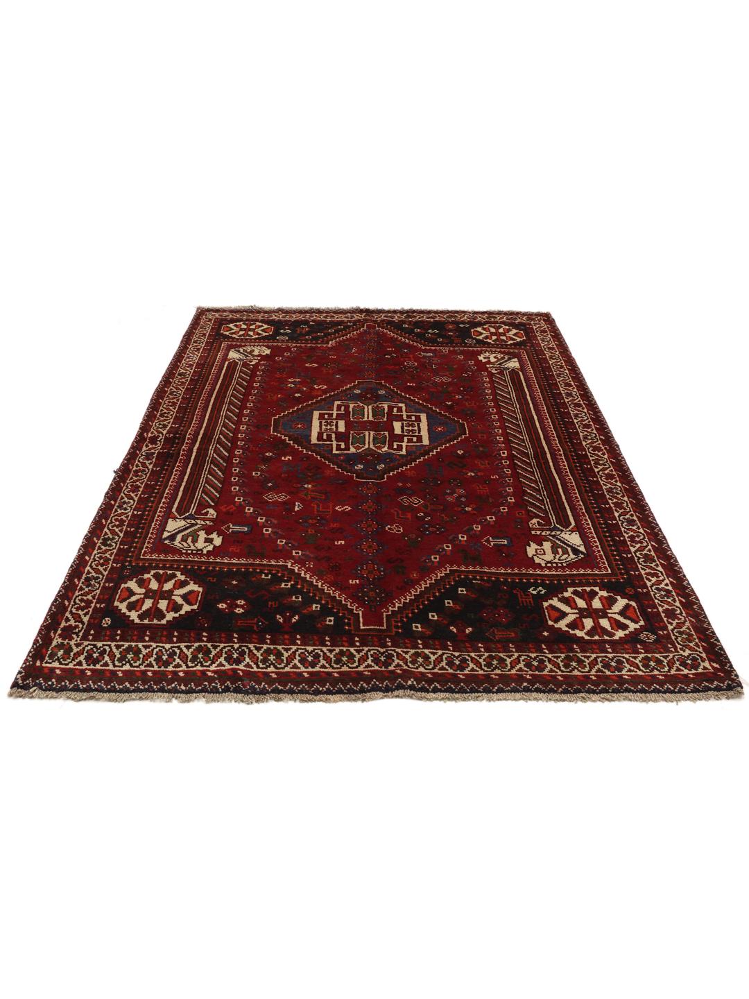 A red hand-knotted wool rug with geometric tribal patterns from the Middle East.