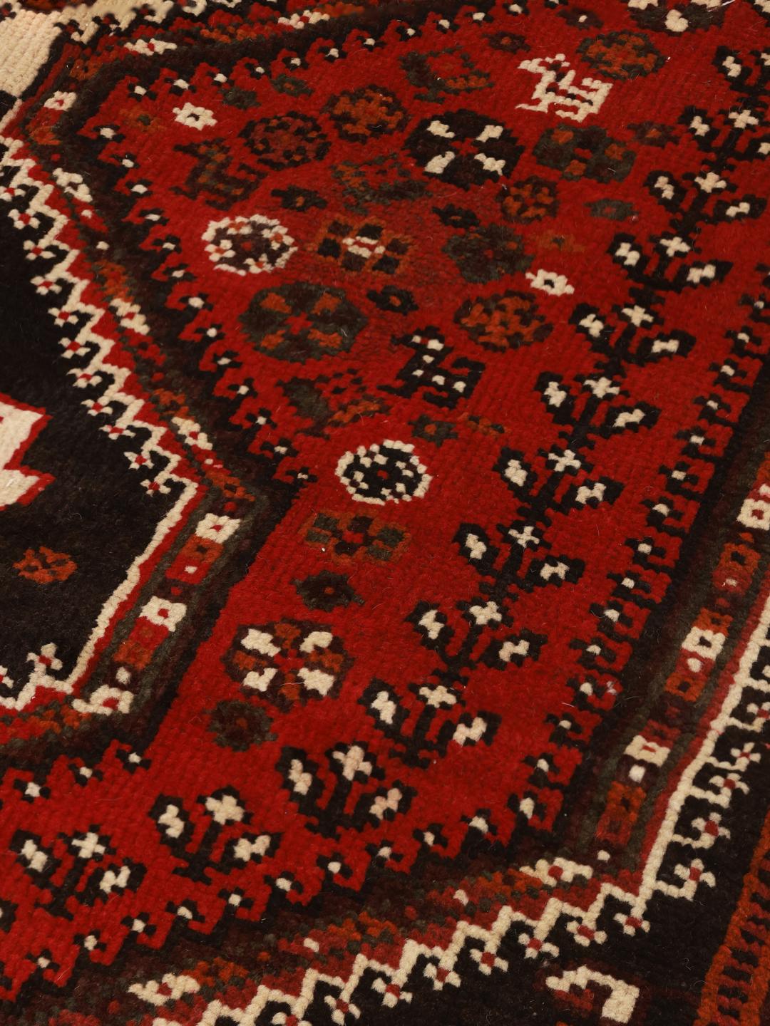 Authentic hand-knotted Ghashghai rug with red and black wool geometric patterns from the Middle East.