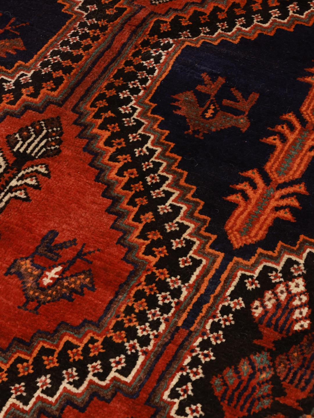 A hand-knotted Qashqai rug from the Middle East featuring a vibrant red and blue geometric pattern.