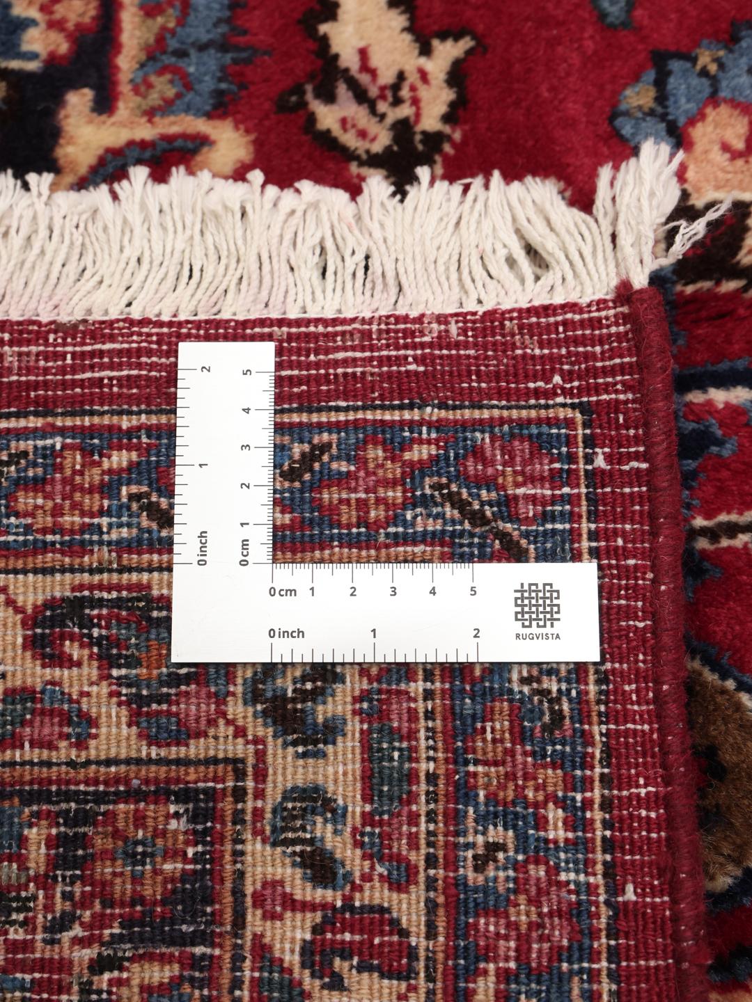 Et håndknyttet Mashad-tæppe fra Mellemøsten med en rød bund og traditionelt medaljonmønster.