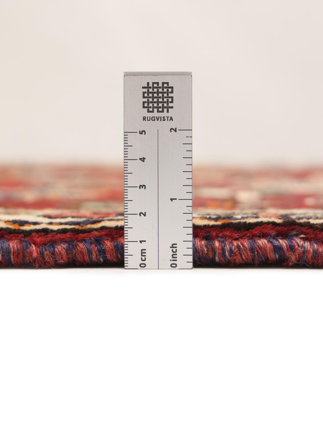 A vibrant red hand-knotted Shiraz rug with intricate geometric tribal patterns and a central medallion.