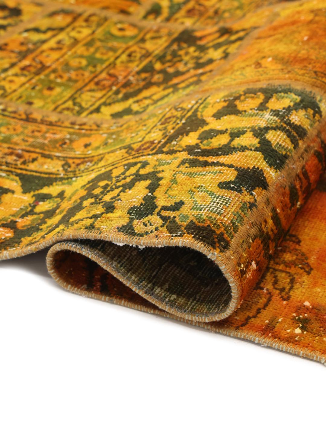Un tapis patchwork coloré avec des tons orange et vert foncé, présentant des motifs vintage complexes.