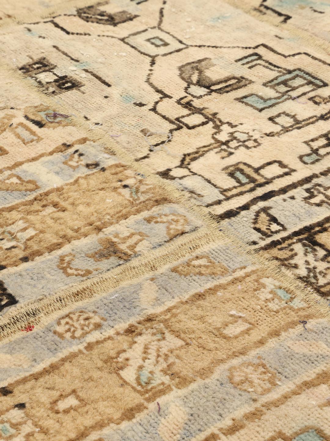 Et unikt patchwork-tæppe med beige, blå og brune toner, der indeholder indviklede geometriske mønstre fra Mellemøsten.