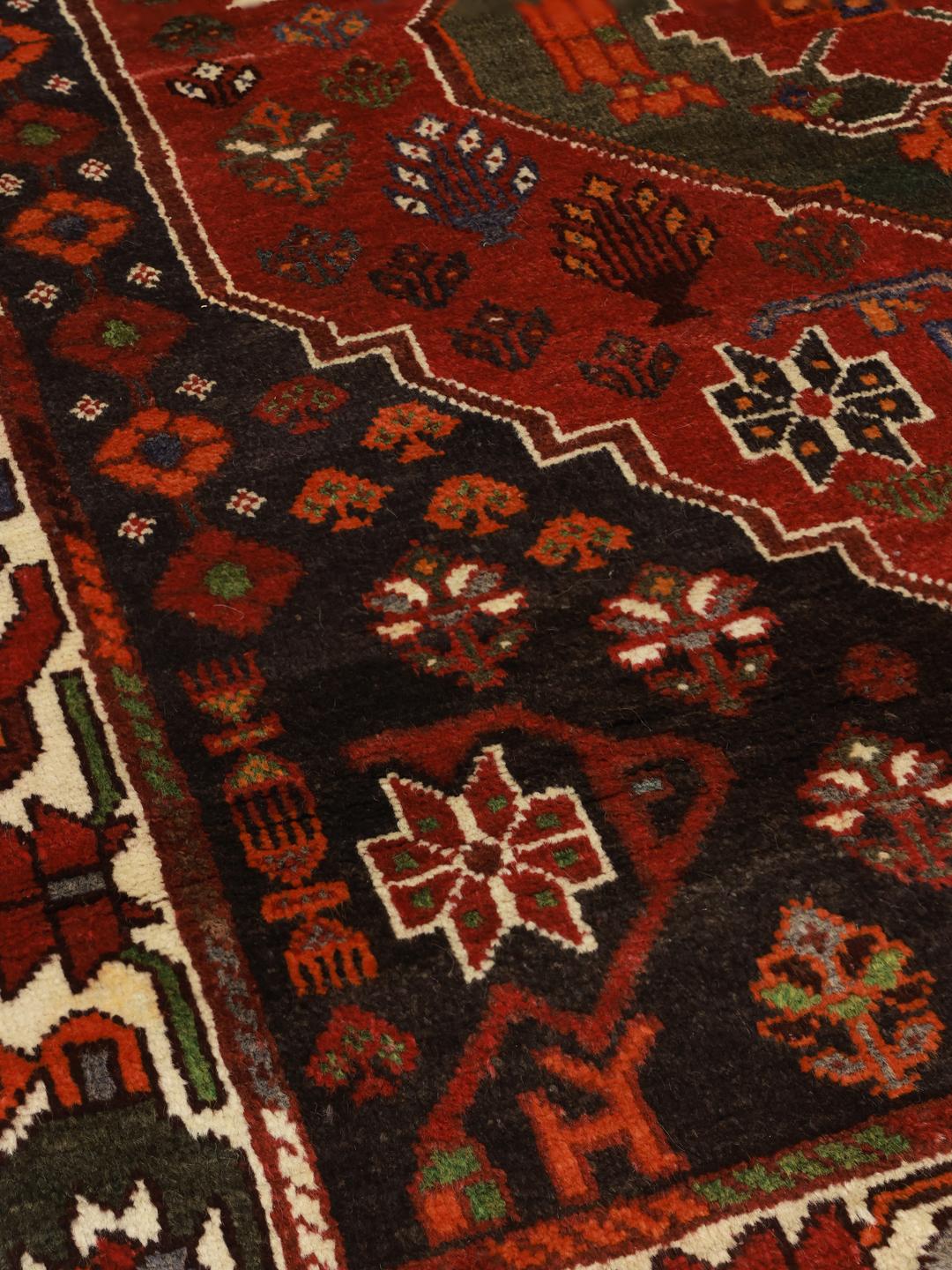 Hand-knotted Shiraz rug from the Middle East featuring a vibrant red and green geometric design.
