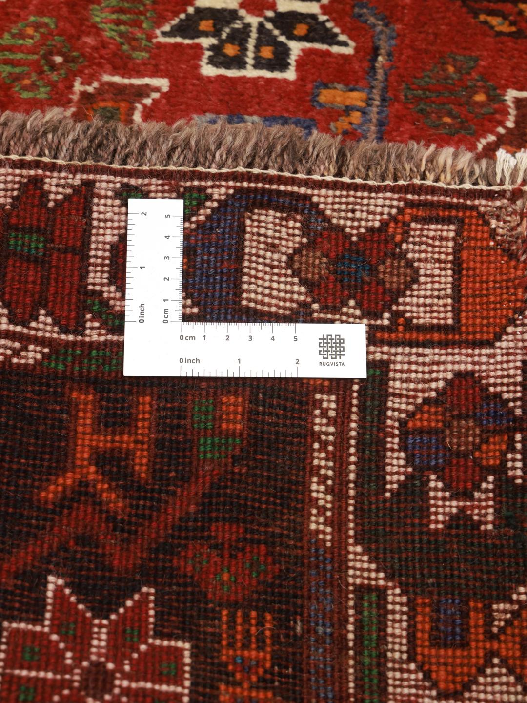 Hand-knotted Shiraz rug from the Middle East featuring a vibrant red and green geometric design.