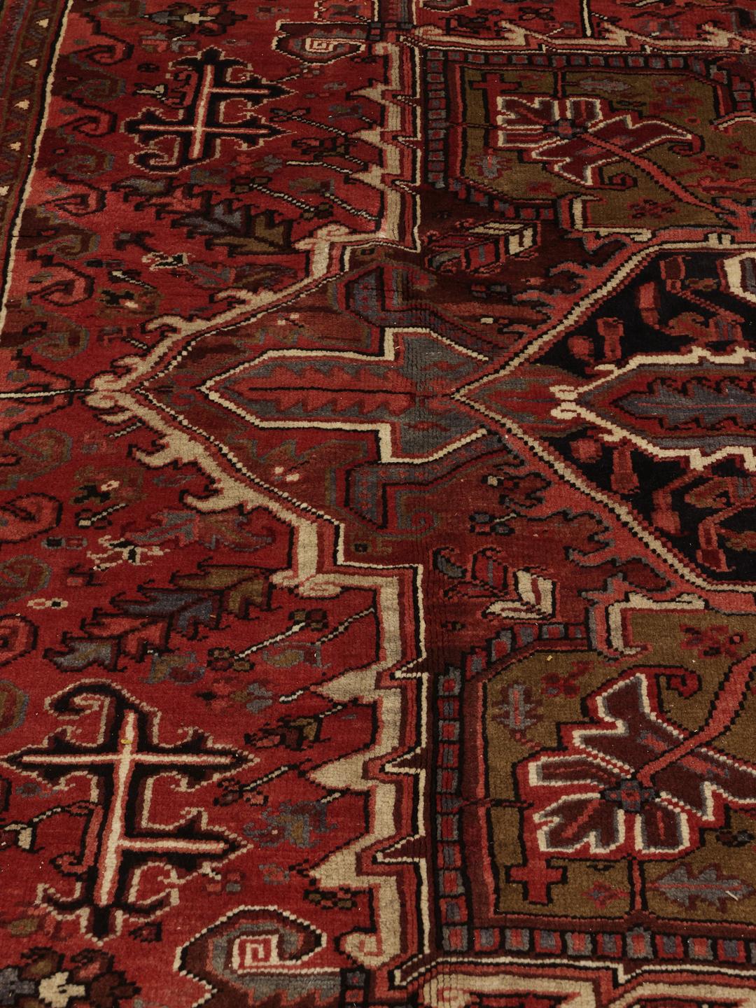 A large, hand-knotted Heriz rug from the Middle East with a red field and geometric medallion.