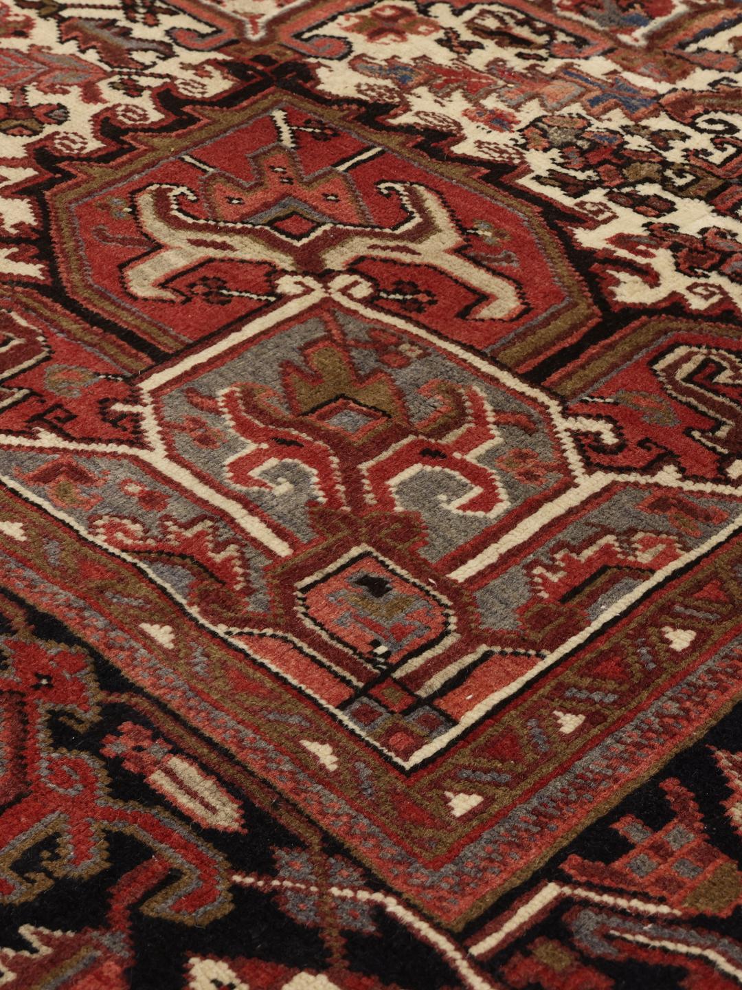 A large, hand-knotted Heriz rug from the Middle East with a red field and geometric medallion.