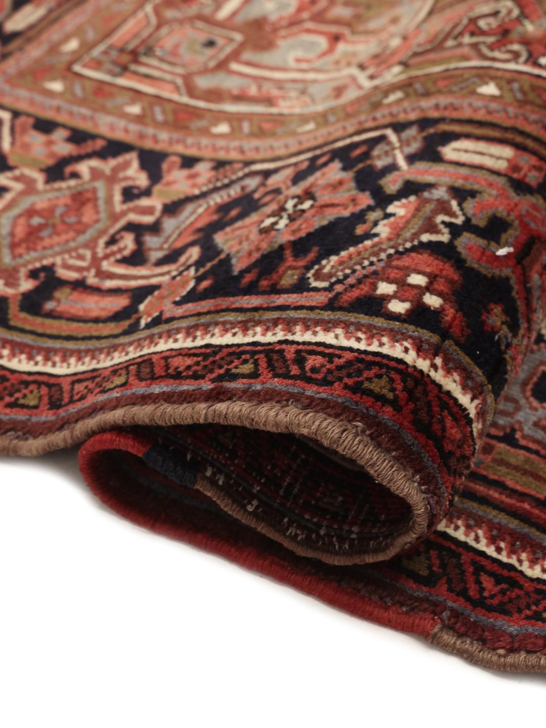 A large, hand-knotted Heriz rug from the Middle East with a red field and geometric medallion.