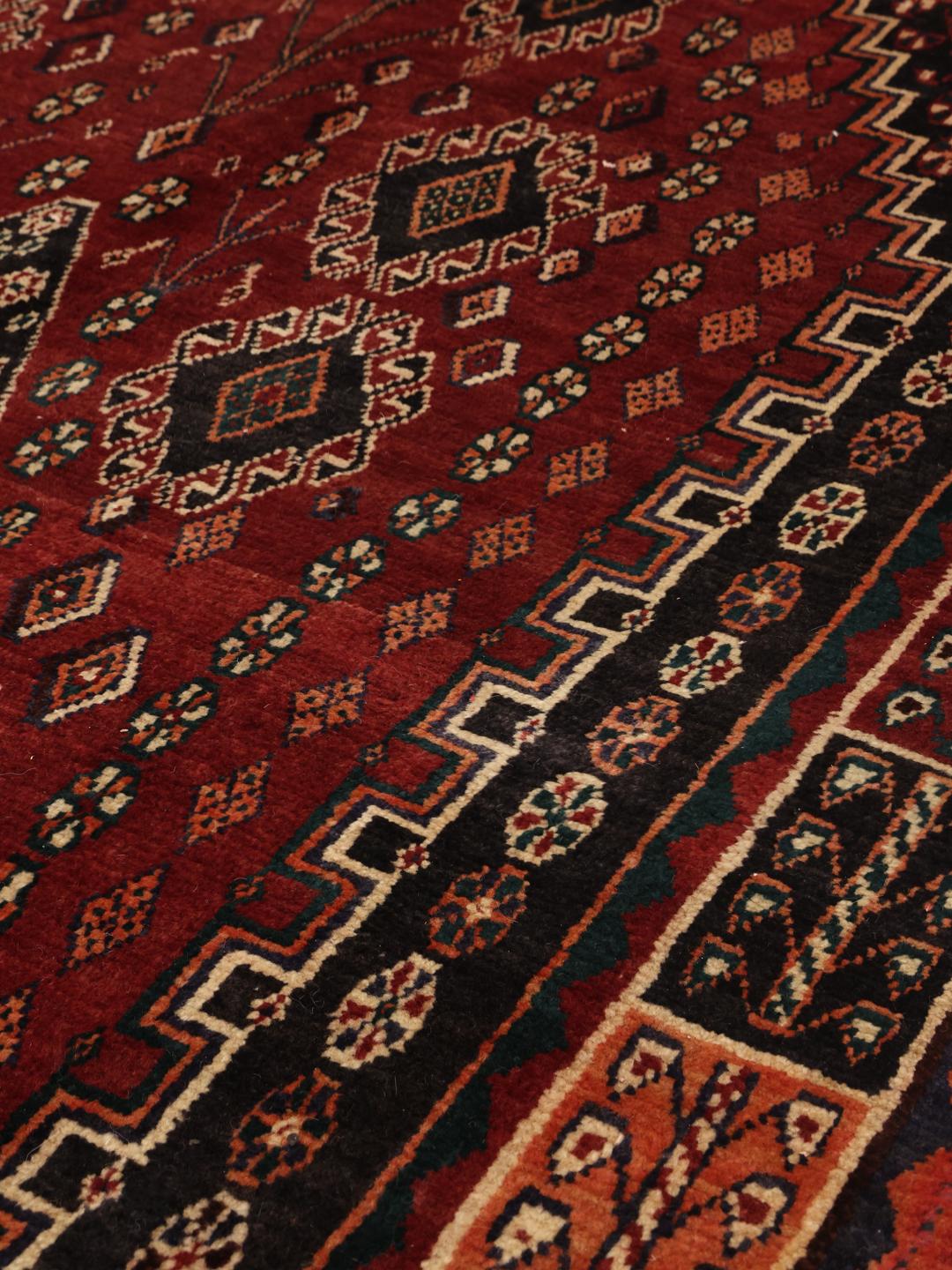 Hand-knotted Ghashghai rug from the Middle East in deep red and black tones
