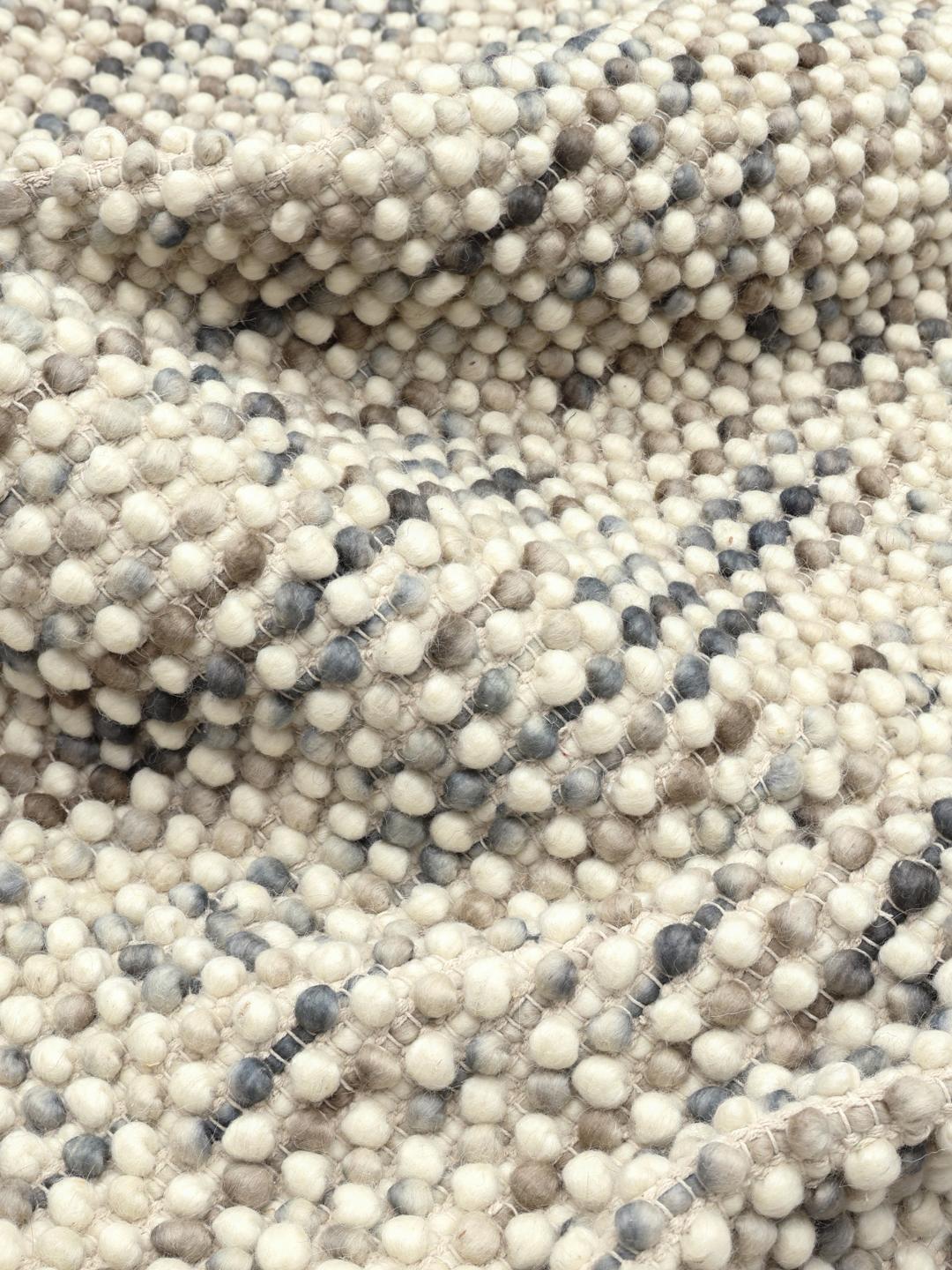 Håndvævet grå og beige tæppe med en struktureret og boblet overflade