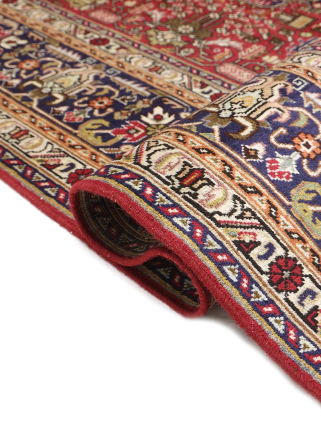 Handmade Tabriz rug from the Middle East featuring a red and blue floral medallion pattern