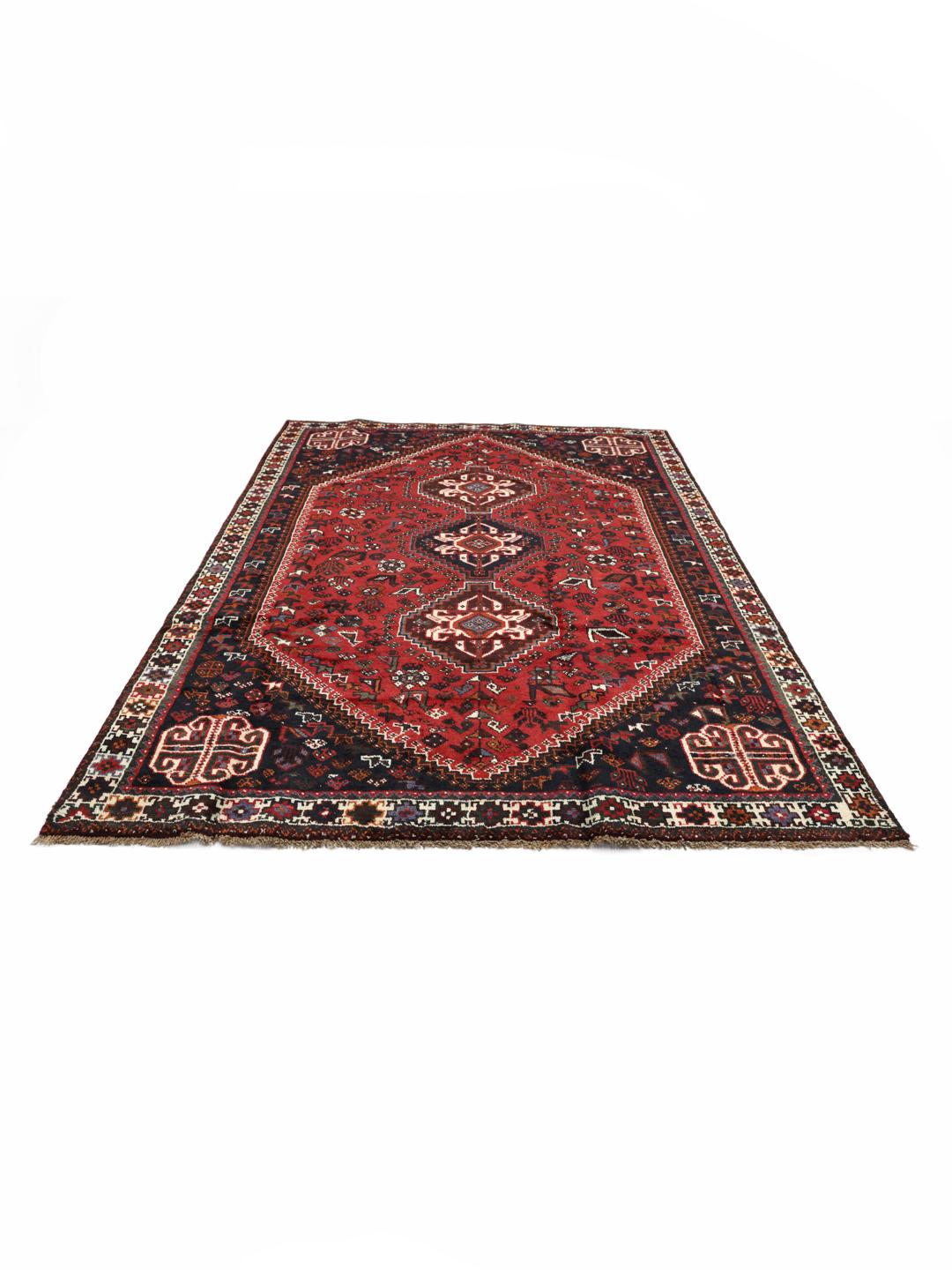 Hand-knotted Qashqai rug with vibrant red and dark tones, originating from the Middle East.