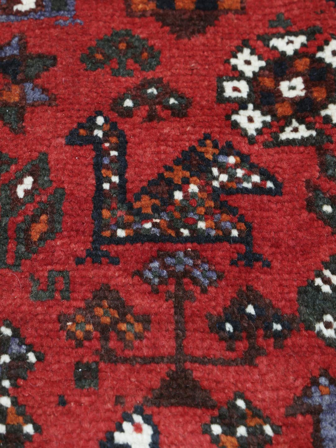 Hand-knotted Qashqai rug with vibrant red and dark tones, originating from the Middle East.