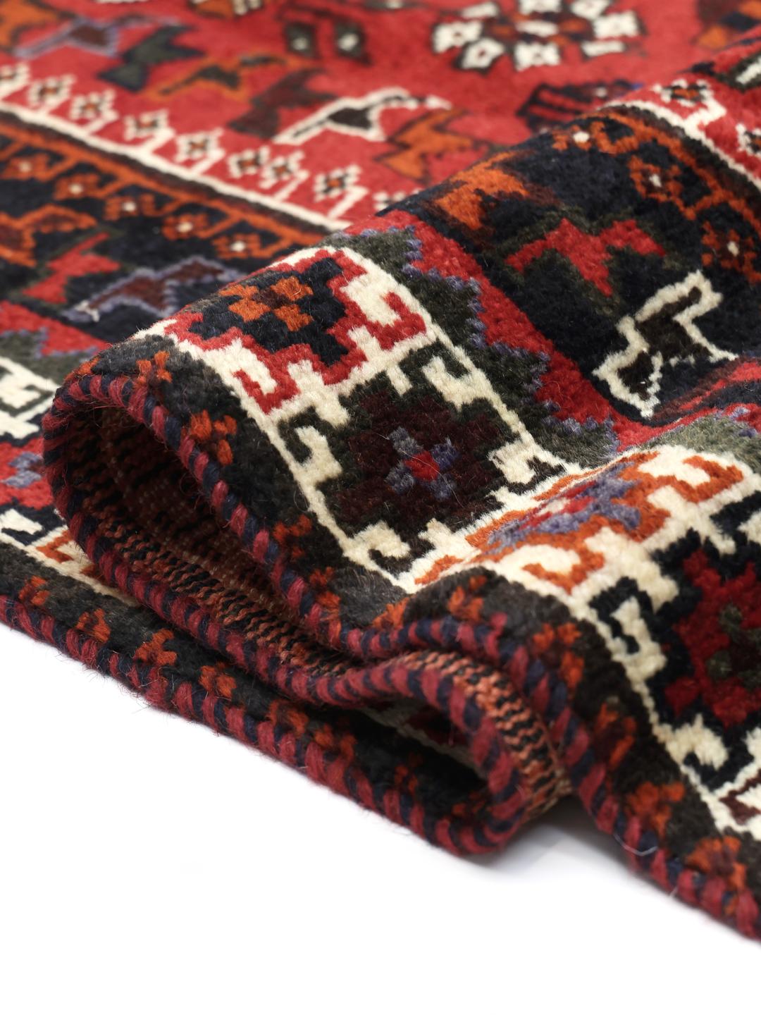 Hand-knotted Qashqai rug with vibrant red and dark tones, originating from the Middle East.