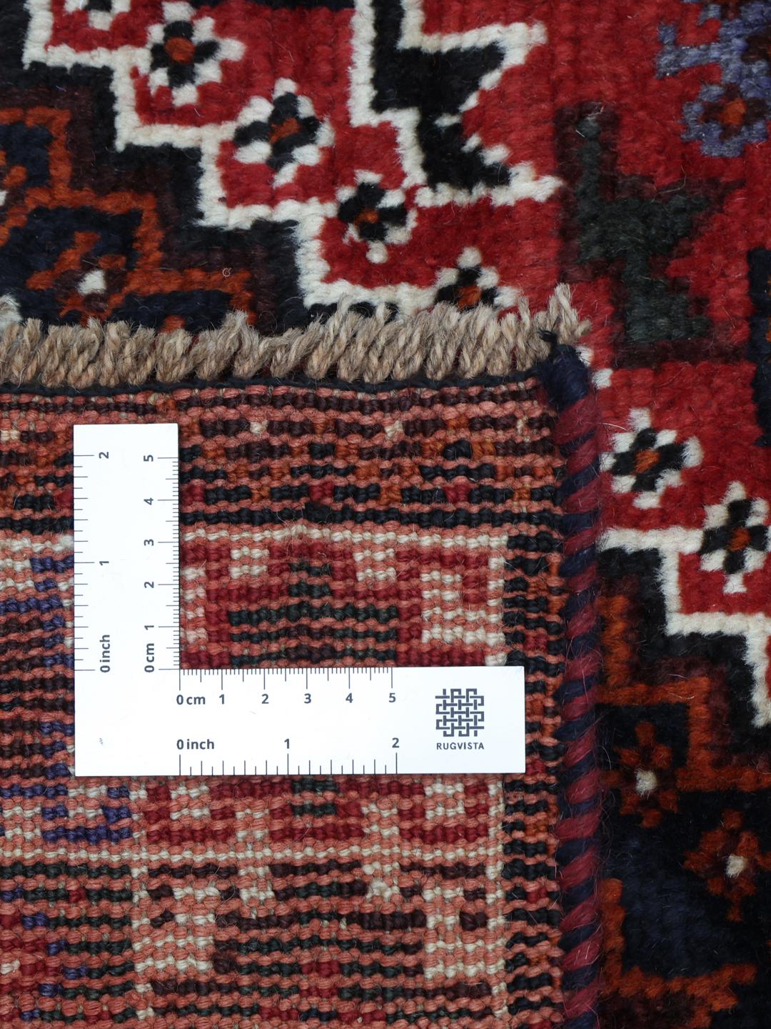Hand-knotted Qashqai rug with vibrant red and dark tones, originating from the Middle East.