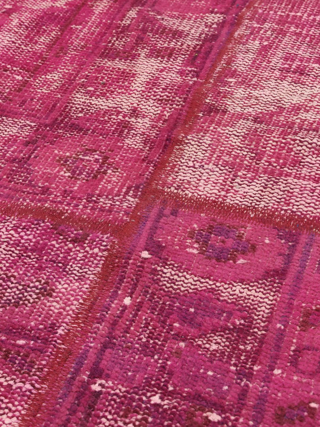 Et rundt, levende pink patchworktæppe med et geometrisk layout, der stammer fra Mellemøsten.