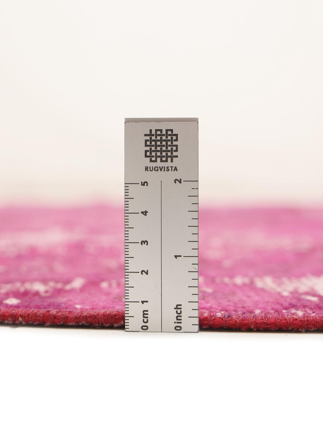 Et rundt, levende pink patchworktæppe med et geometrisk layout, der stammer fra Mellemøsten.