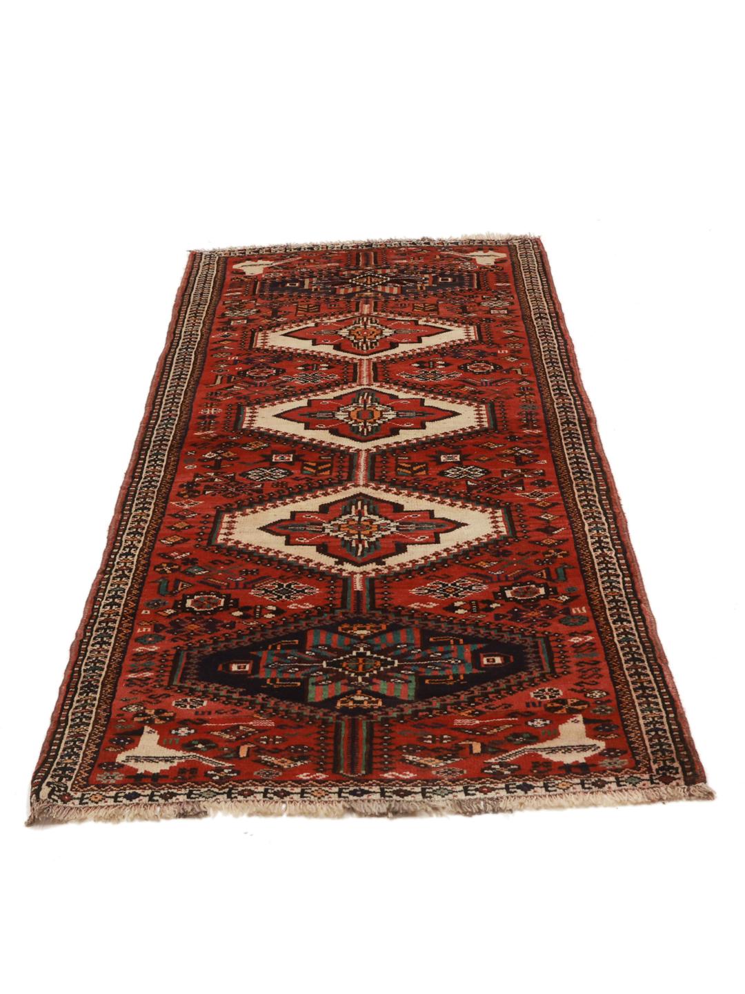 A hand-knotted Shiraz rug from the Middle East featuring a red field with geometric medallions.