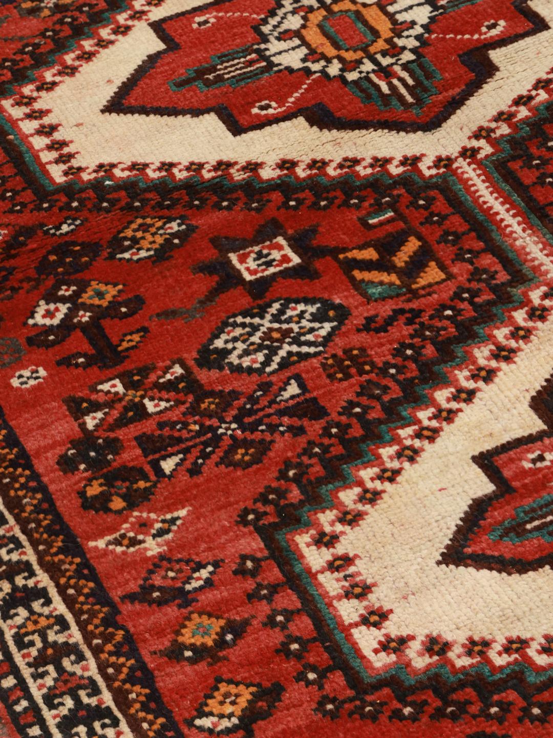 A hand-knotted Shiraz rug from the Middle East featuring a red field with geometric medallions.