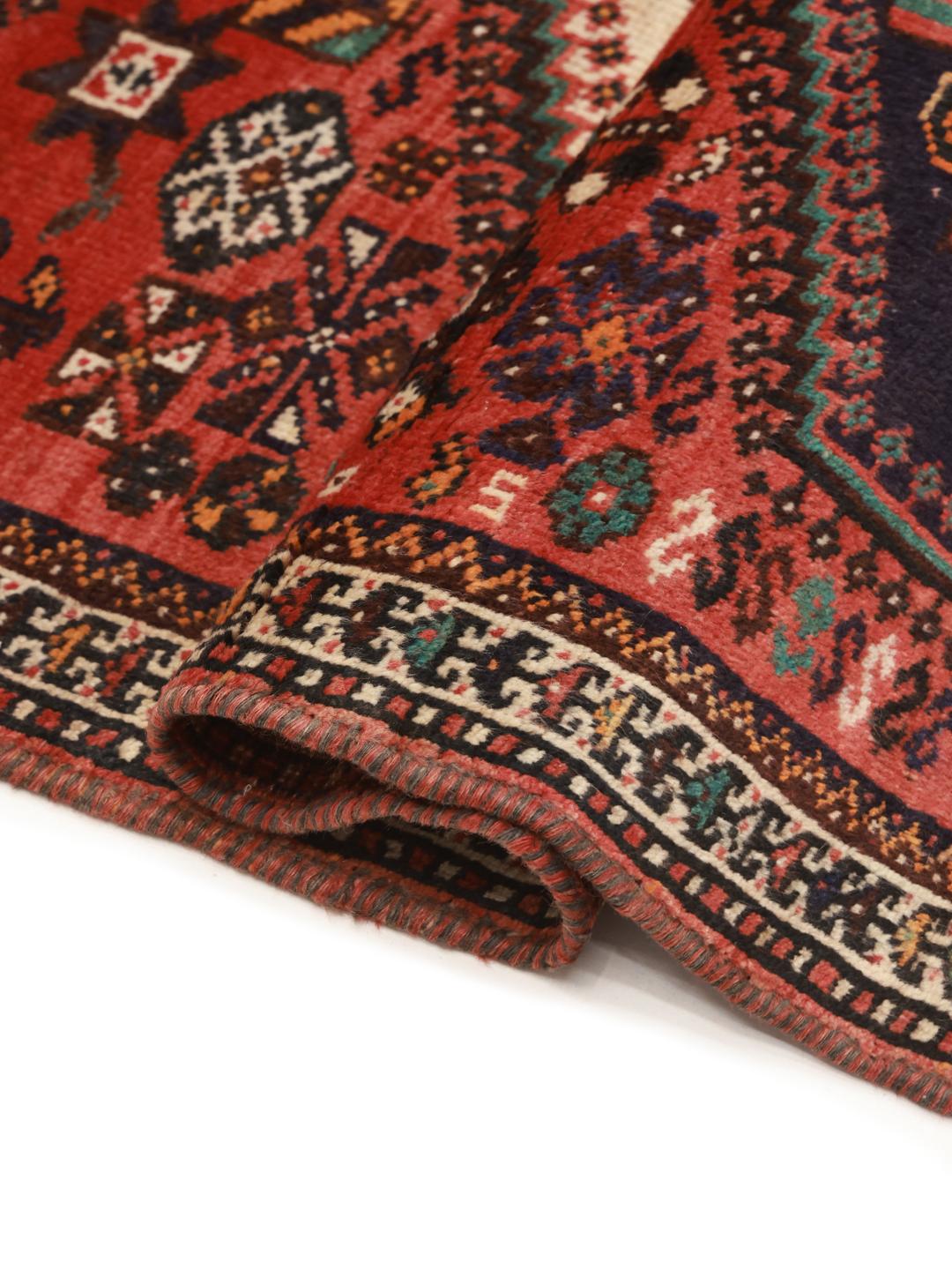 A hand-knotted Shiraz rug from the Middle East featuring a red field with geometric medallions.