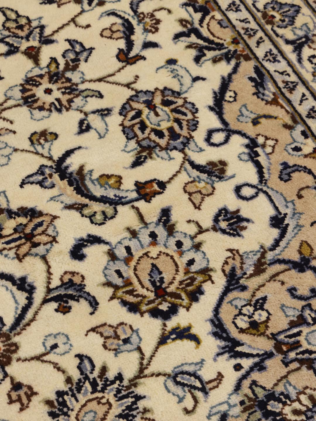 A hand-knotted Keshan rug from the Middle East with a cream background and floral motifs.