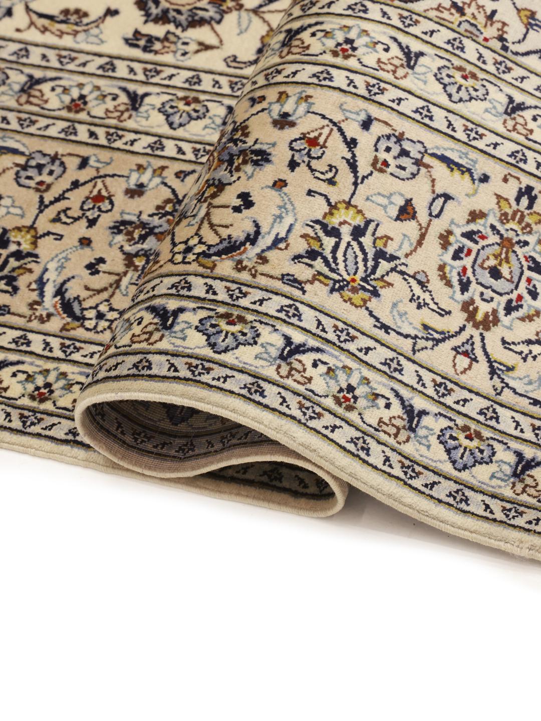 A hand-knotted Keshan rug from the Middle East with a cream background and floral motifs.