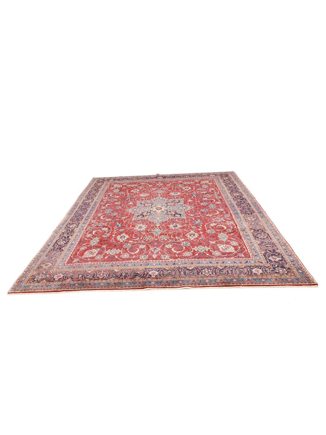 A hand-knotted Sarough rug from the Middle East featuring a vibrant red field with blue floral accents.