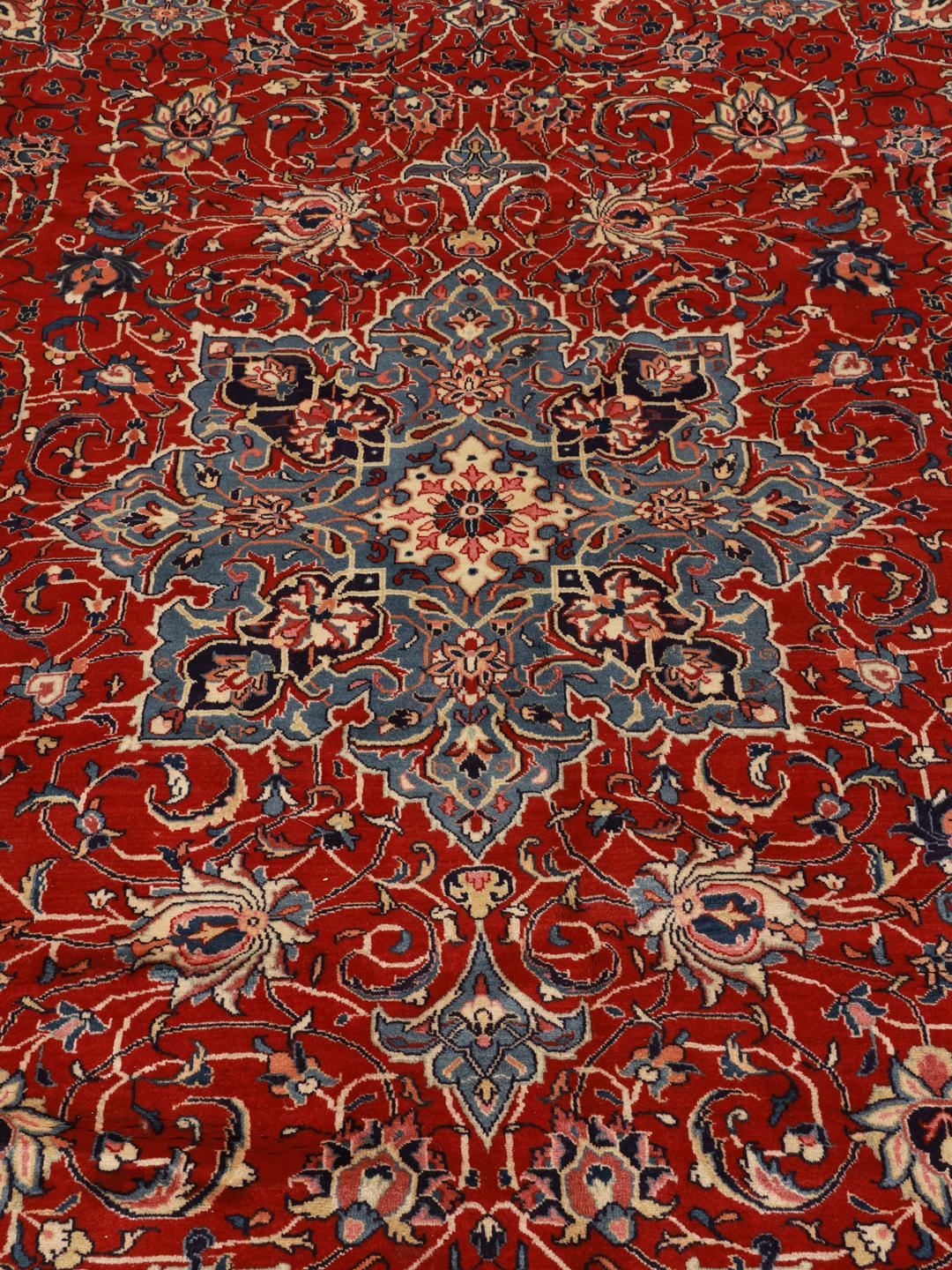 A hand-knotted Sarough rug from the Middle East featuring a vibrant red field with blue floral accents.