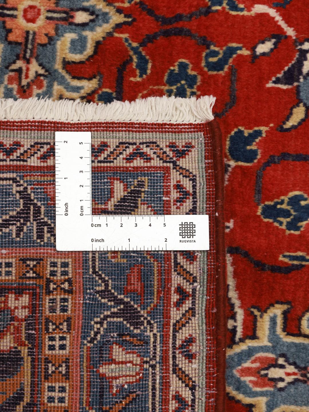 A hand-knotted Sarough rug from the Middle East featuring a vibrant red field with blue floral accents.