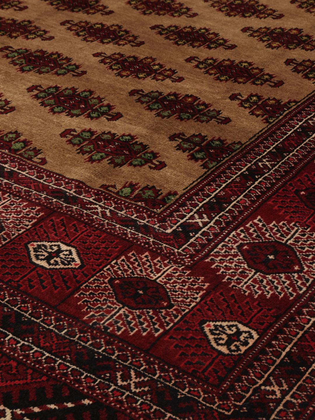 Hand-knotted Turkaman rug from the Middle East in deep red and beige tones.