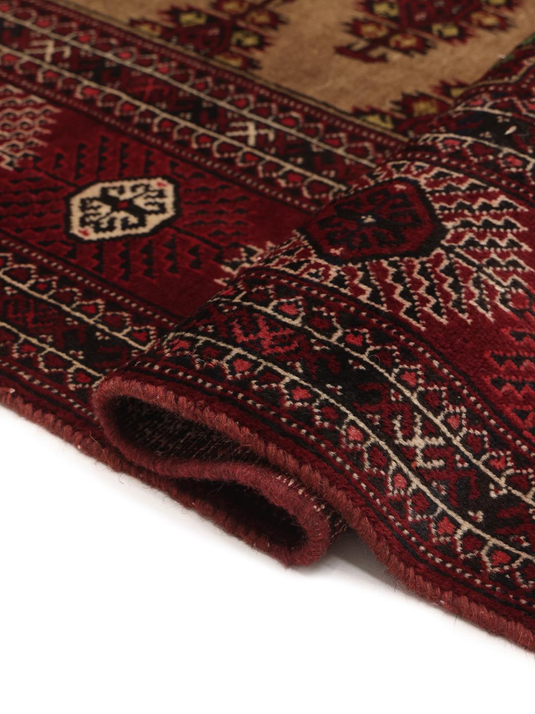 Hand-knotted Turkaman rug from the Middle East in deep red and beige tones.