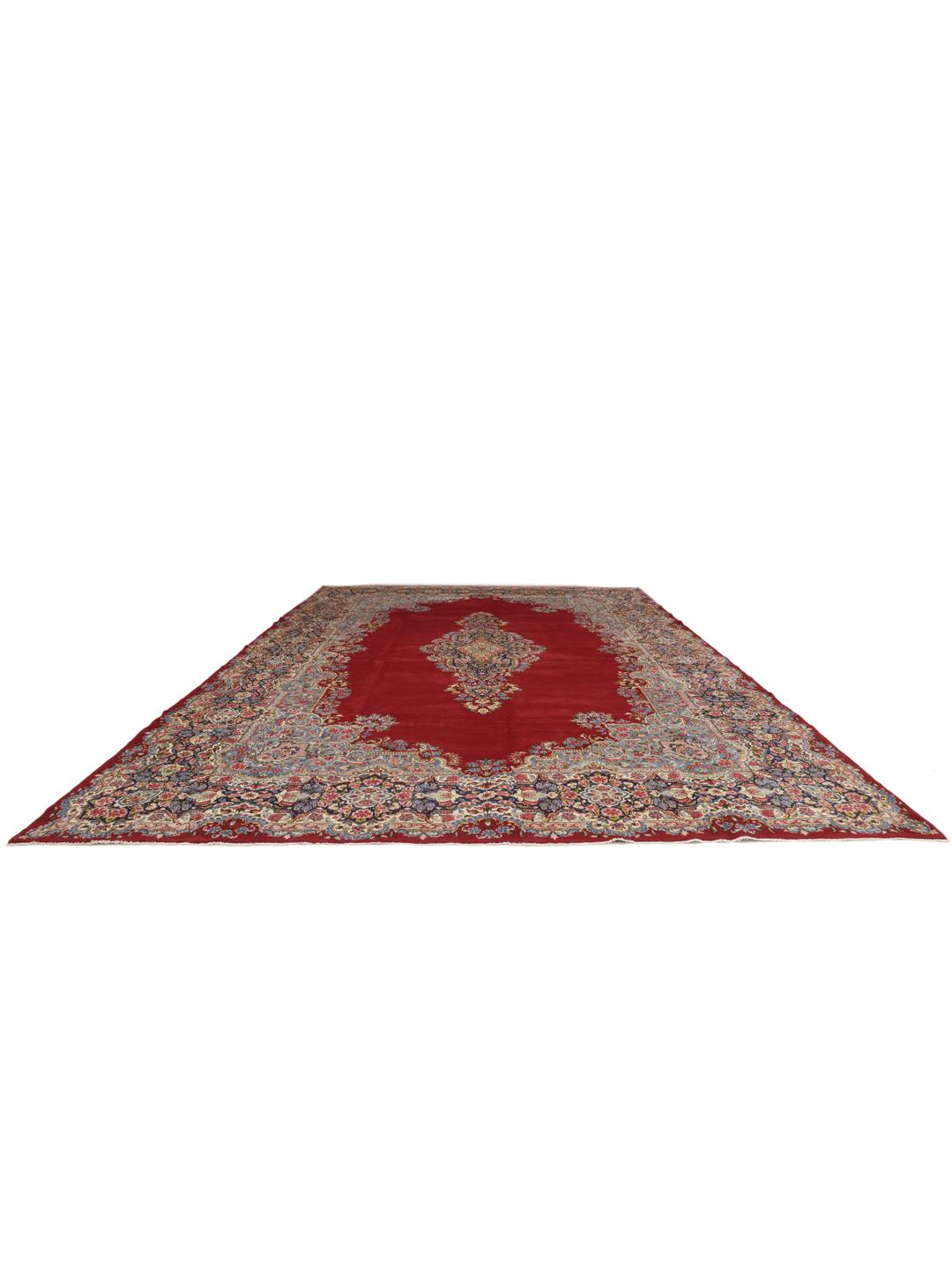 Een groot, rechthoekig Kerman-tapijt uit het Midden-Oosten met een donkerrood veld en een ingewikkeld bloemmedaillon.