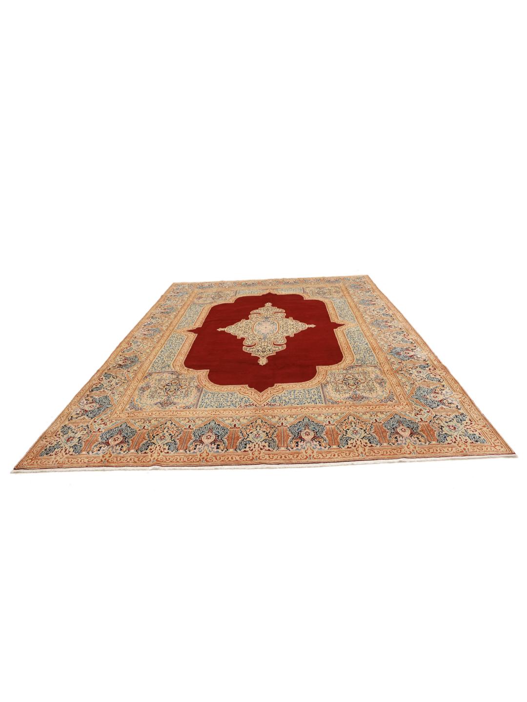 Een groot rechthoekig Kerman-tapijt uit het Midden-Oosten met een rood veld en een ingewikkeld blauw en beige medaillon.