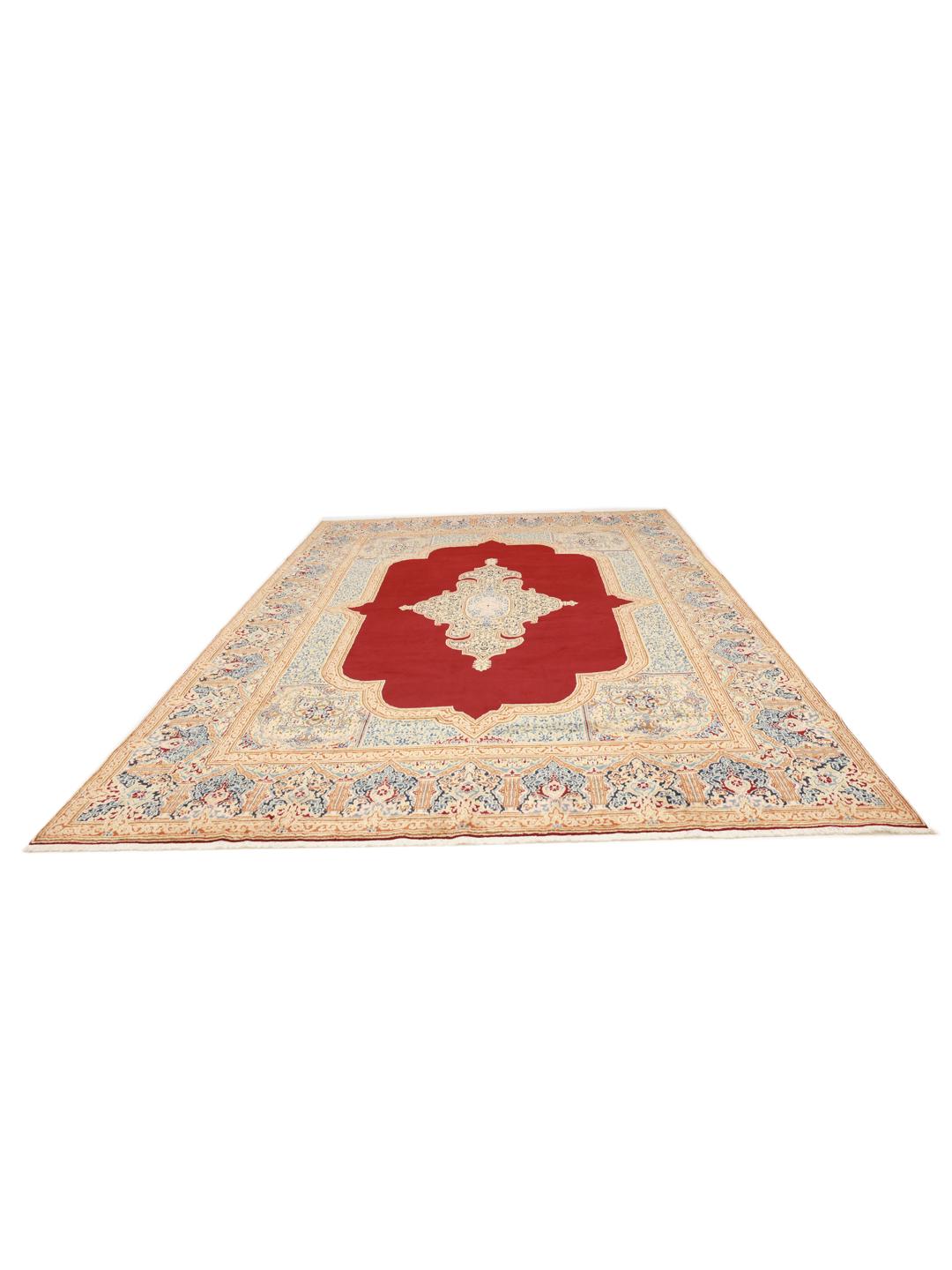 Een groot rechthoekig Kerman-tapijt uit het Midden-Oosten met een rood veld en een ingewikkeld blauw en beige medaillon.
