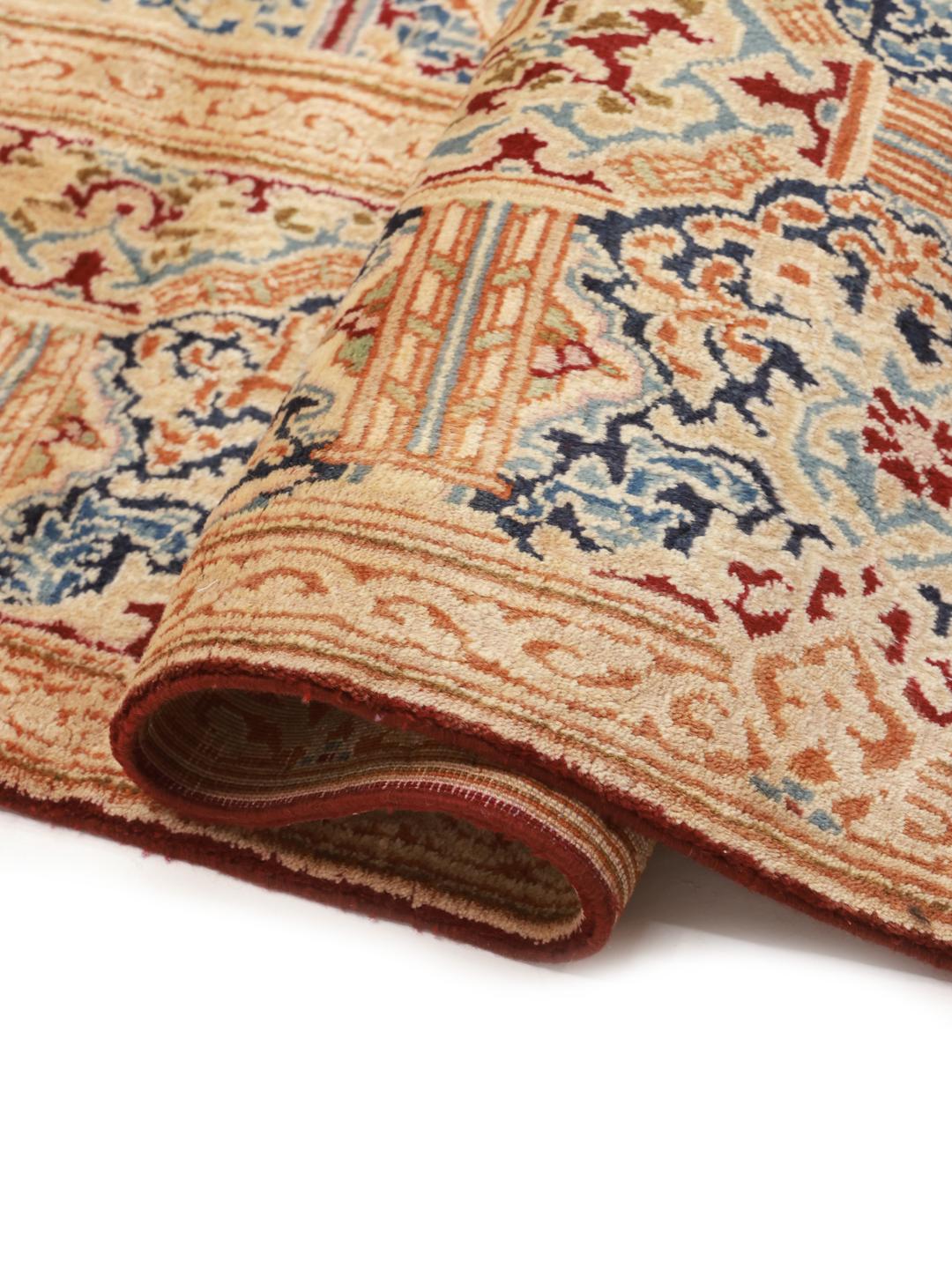 Een groot rechthoekig Kerman-tapijt uit het Midden-Oosten met een rood veld en een ingewikkeld blauw en beige medaillon.