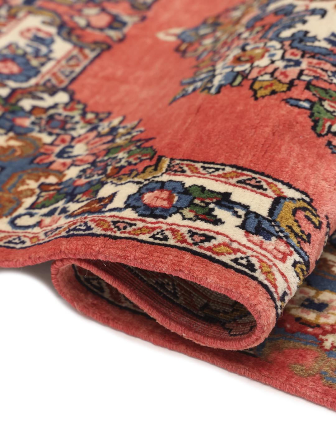 A hand-knotted Sarough rug from the Middle East featuring a vibrant red field and a detailed floral medallion.