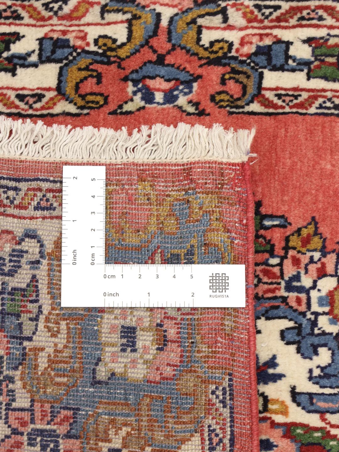 A hand-knotted Sarough rug from the Middle East featuring a vibrant red field and a detailed floral medallion.