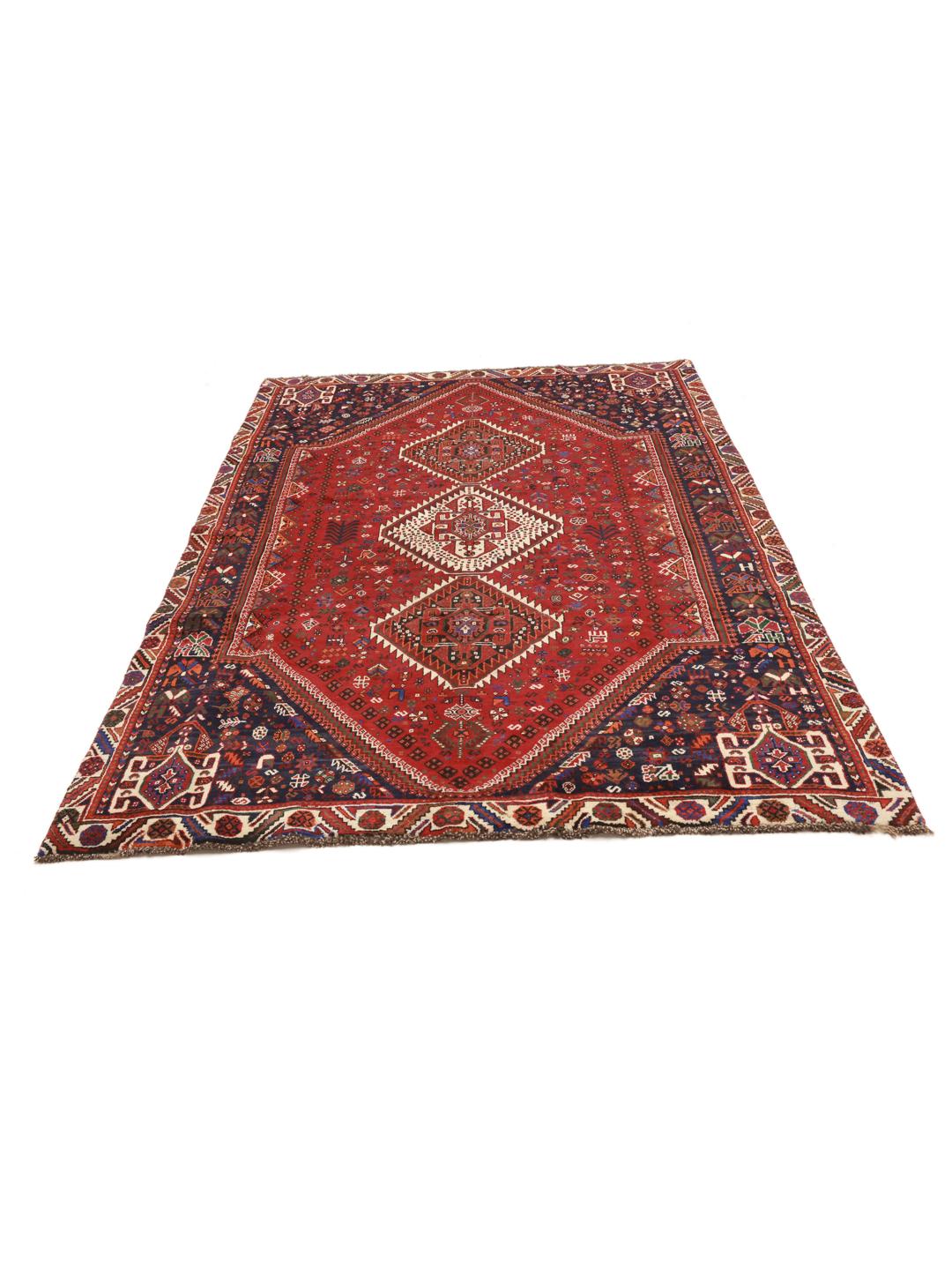 A hand-knotted Qashqai rug from the Middle East featuring a vibrant red and navy blue geometric tribal pattern.