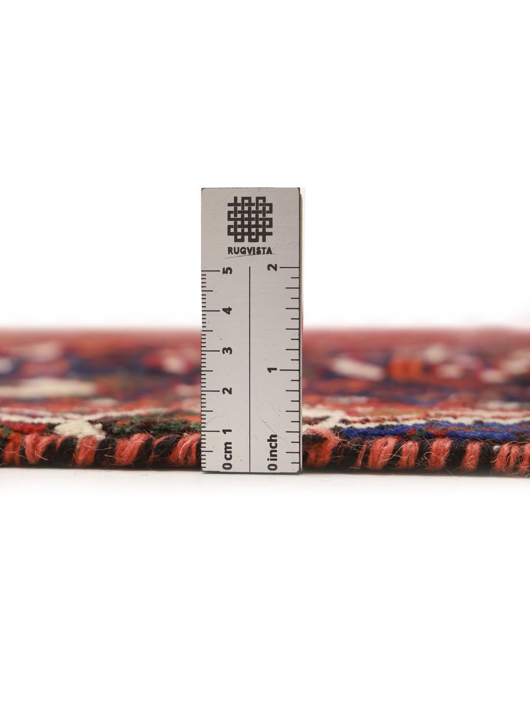 A hand-knotted Qashqai rug from the Middle East featuring a vibrant red and navy blue geometric tribal pattern.