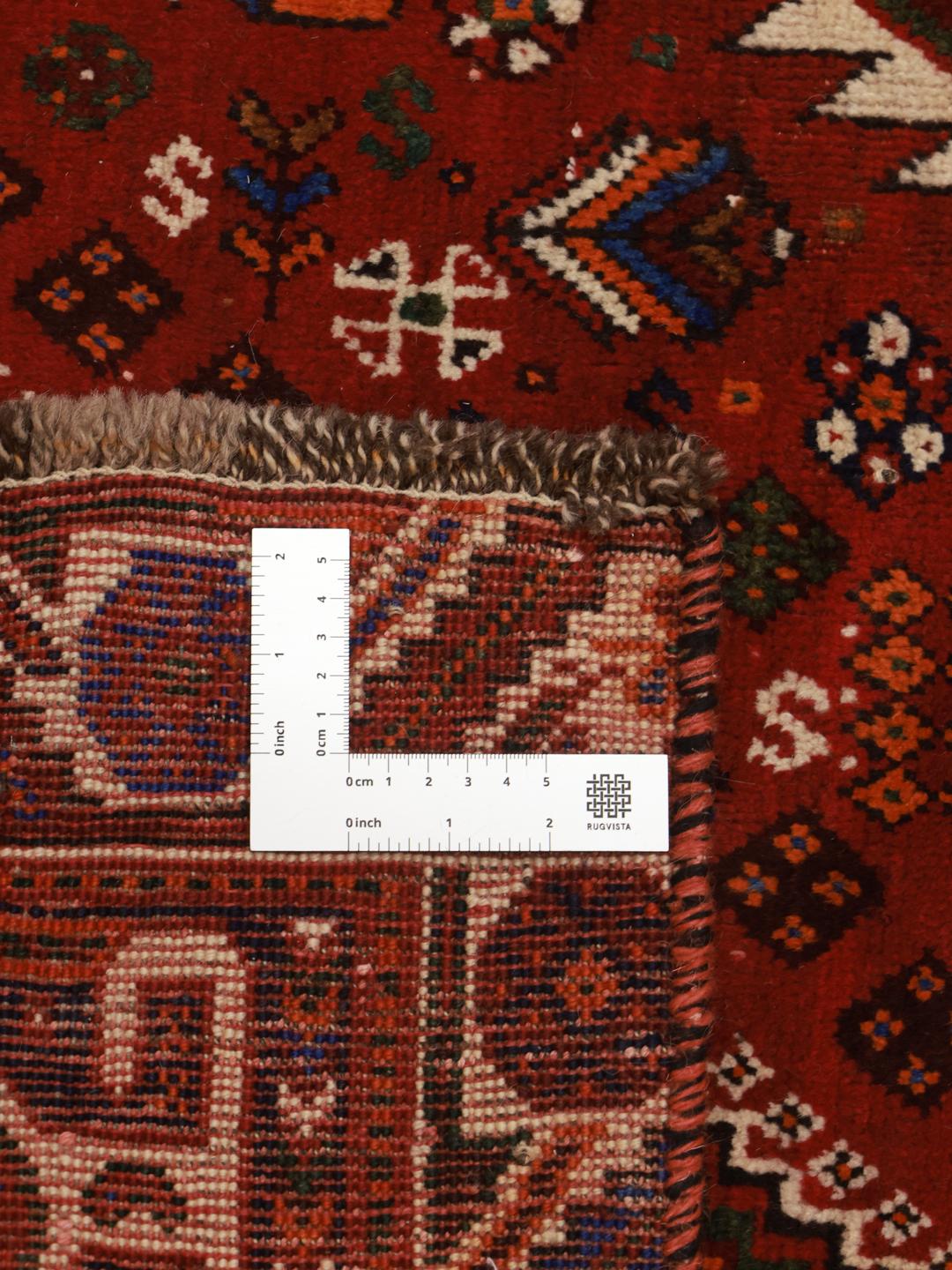 A hand-knotted Qashqai rug from the Middle East featuring a vibrant red and navy blue geometric tribal pattern.