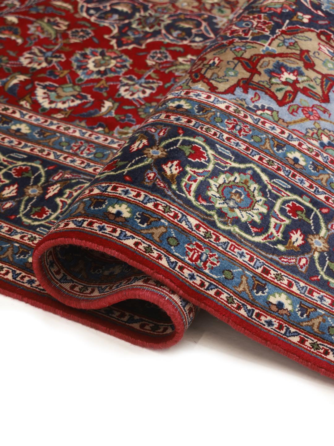 A hand-knotted Mashad rug from the Middle East with a deep red field and ornate patterns.
