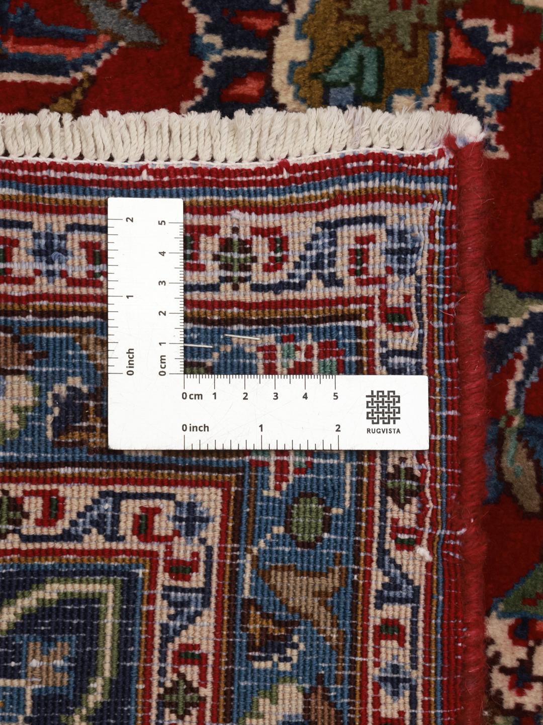 A hand-knotted Mashad rug from the Middle East with a deep red field and ornate patterns.