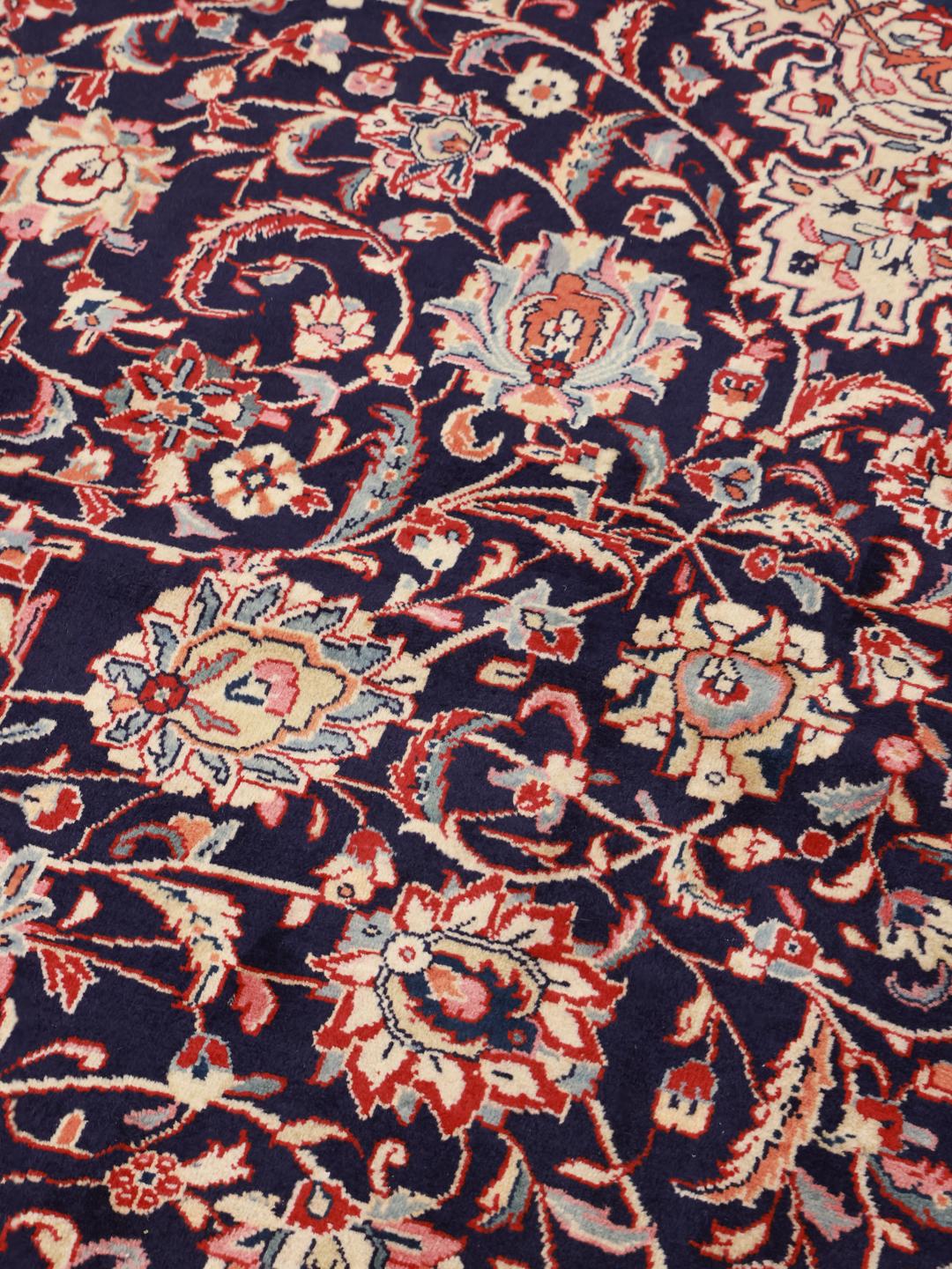 Een groot rechthoekig Mahal tapijt uit het Midden-Oosten met een donkerblauw veld en rode randen.