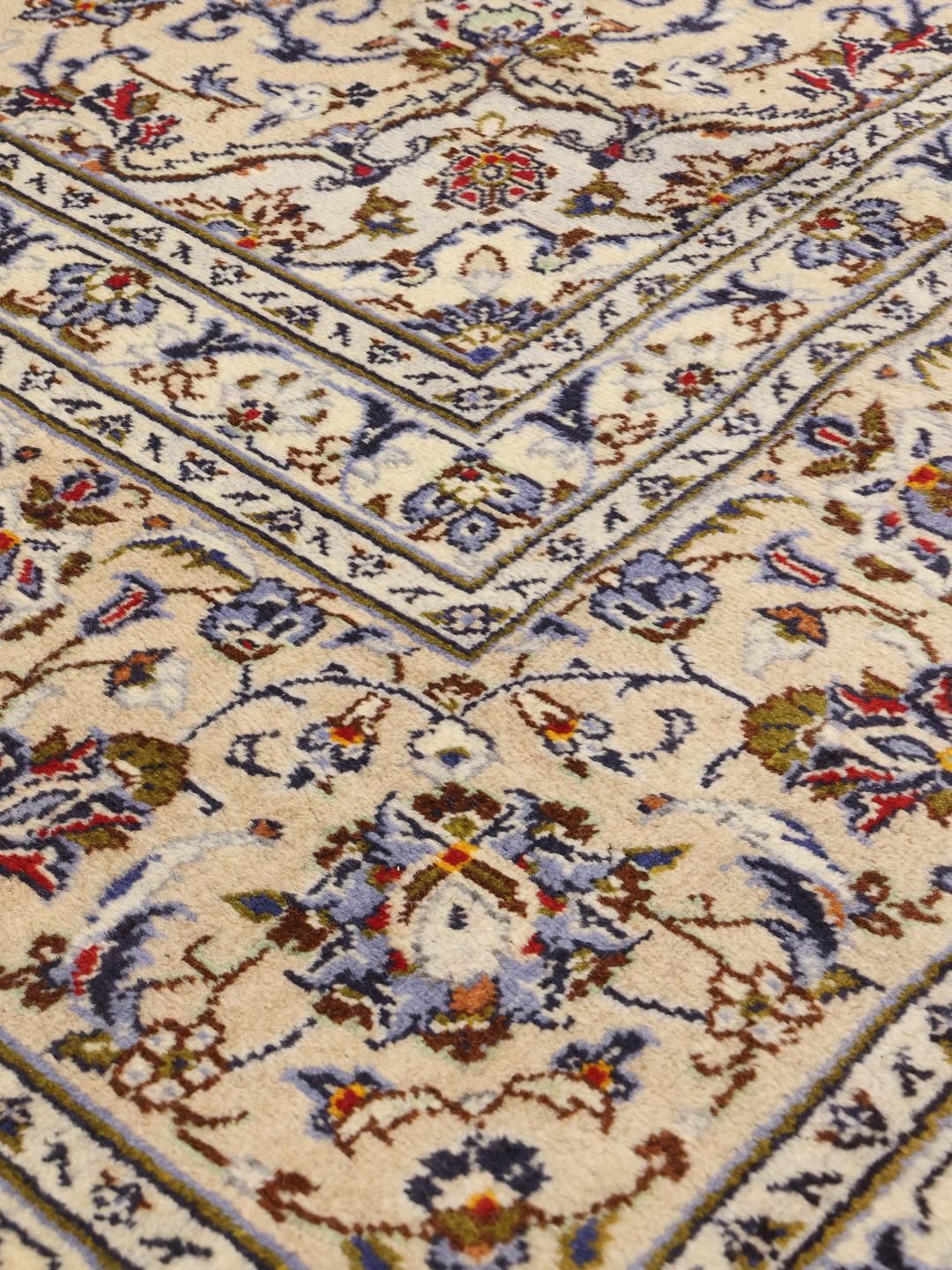 A large rectangular Keshan rug with a beige field and intricate floral medallion from the Middle East.