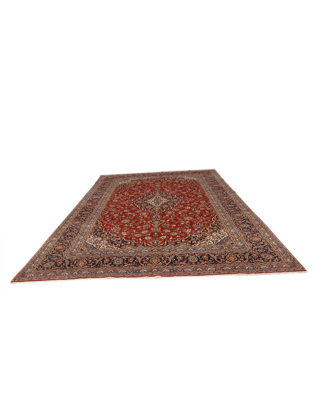 A large, hand-knotted Keshan rug from the Middle East with a deep red floral field and navy border.