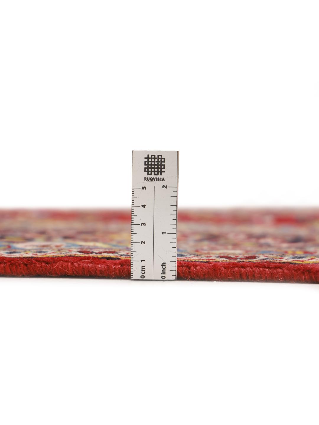 A large, hand-knotted Keshan rug from the Middle East with a deep red floral field and navy border.