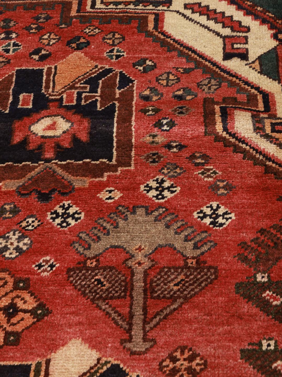 Een handgeknoopt Hamadan-tapijt uit het Midden-Oosten met een rood veld en traditionele geometrische motieven.