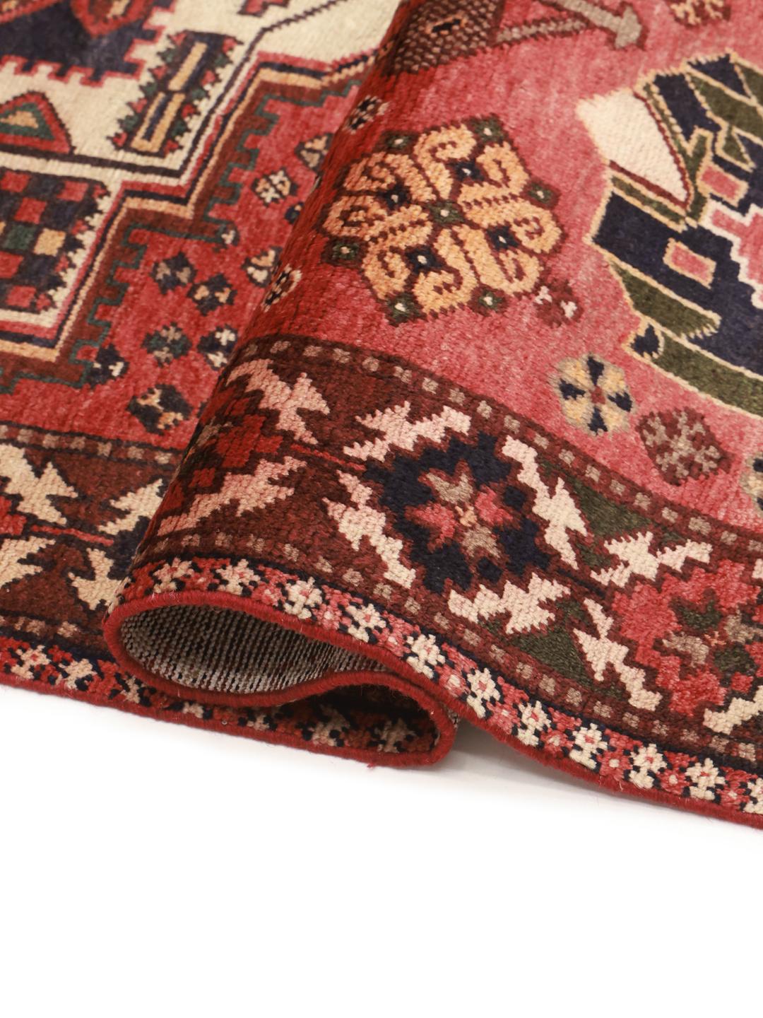 Een handgeknoopt Hamadan-tapijt uit het Midden-Oosten met een rood veld en traditionele geometrische motieven.