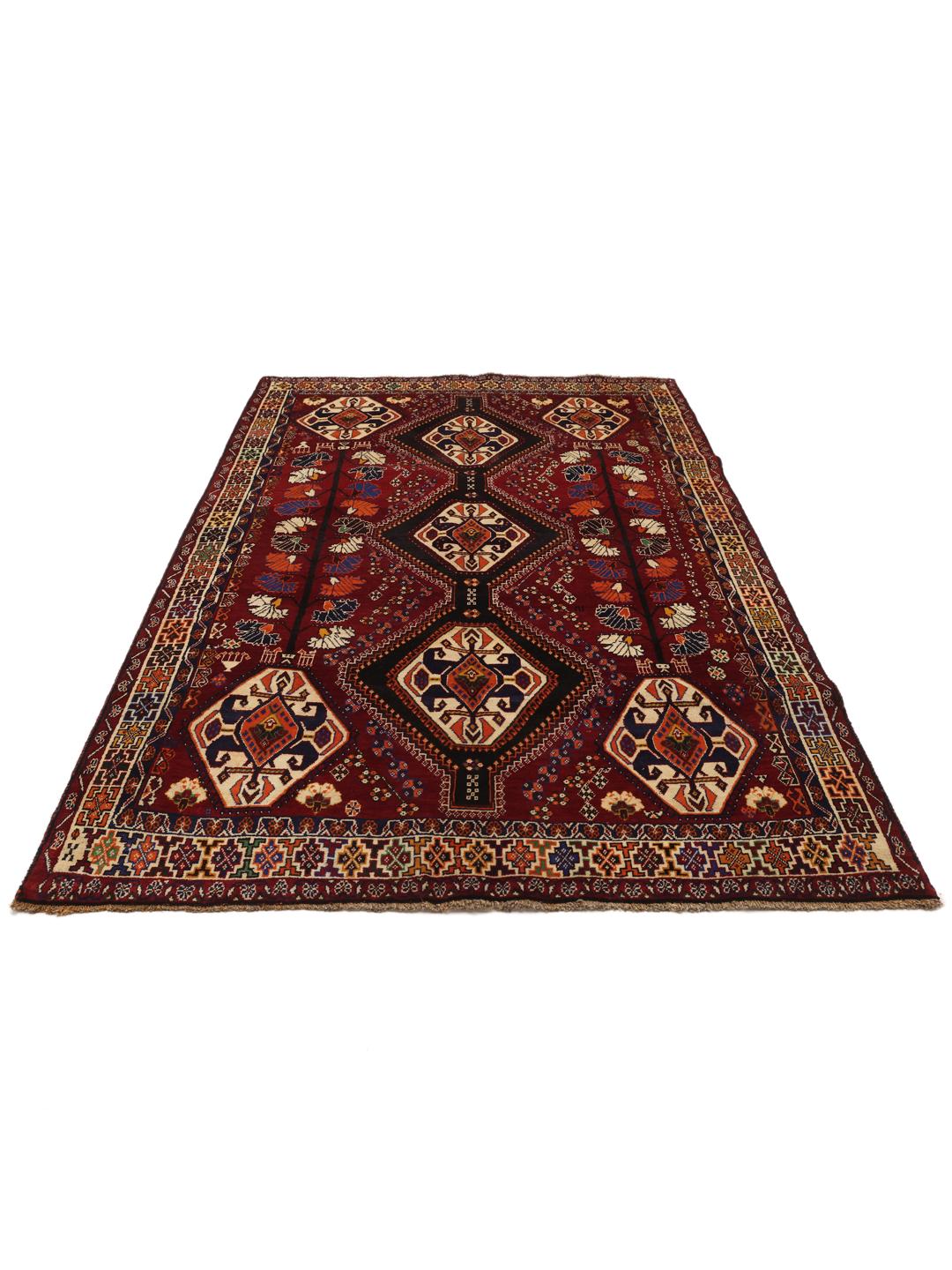 A hand-knotted Qashqai rug from the Middle East featuring a vibrant red field and geometric medallion patterns.