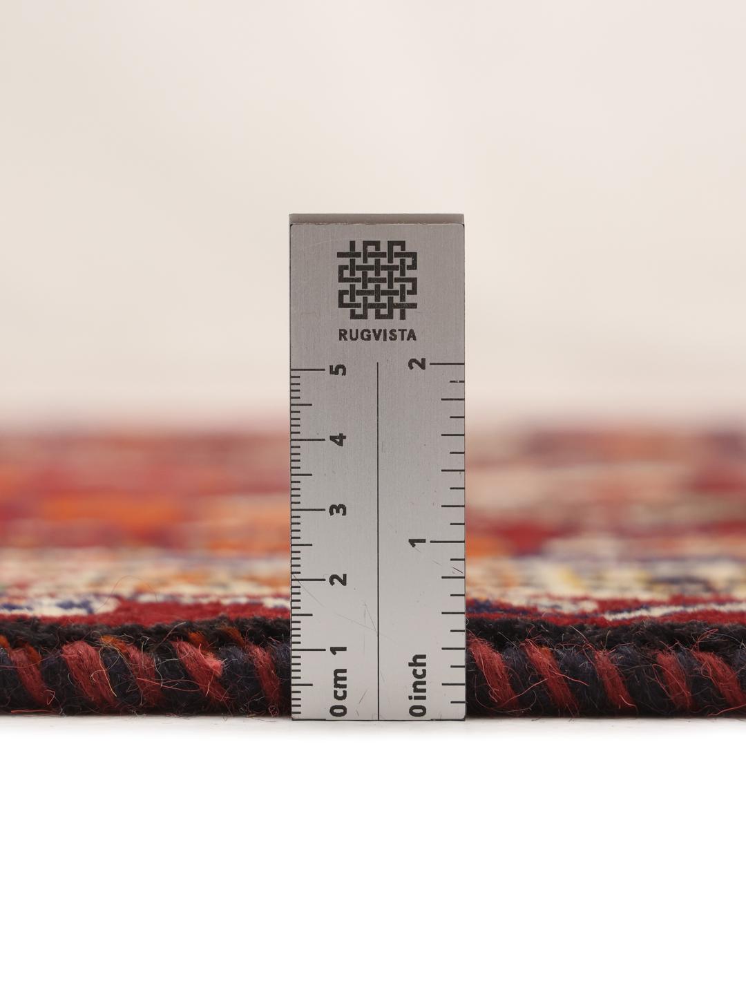 A hand-knotted Qashqai rug from the Middle East featuring a vibrant red field and geometric medallion patterns.